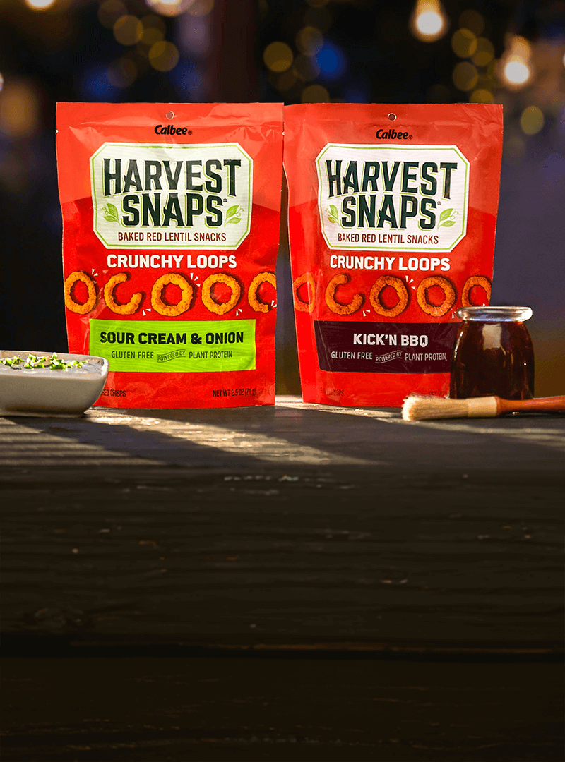 Harvest Snaps Crunchy Loops Sour cream & onion and Kick'N BBQ in backyard theme.