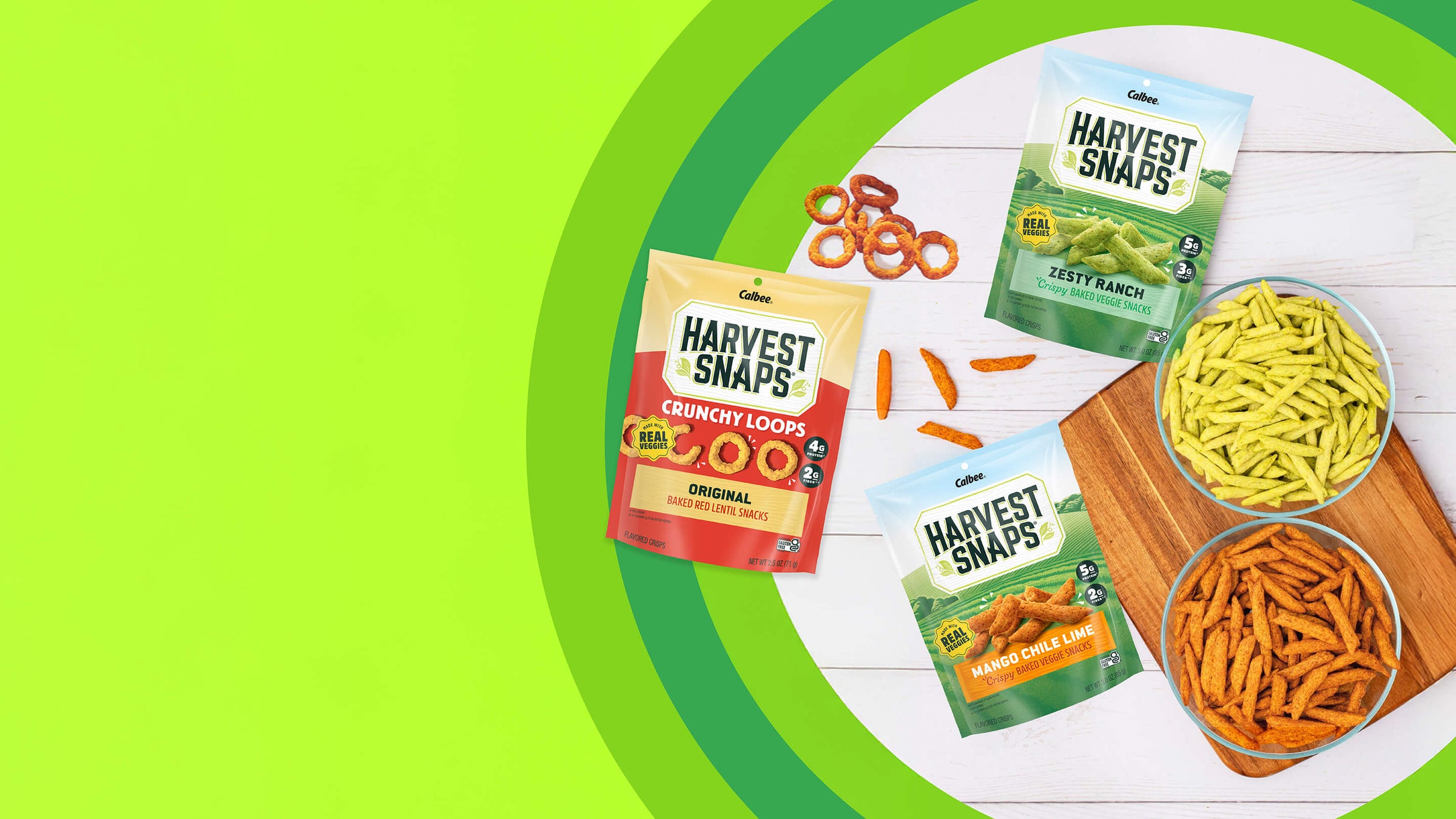 A bright green background highlights three Harvest Snaps snack bags labeled "Crunchy Loops," "Zesty Ranch," and "Mango Chile Lime." Two bowls are filled with crunchy snacks, exuding a fresh, vibrant feel.