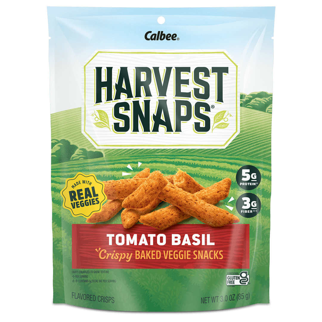 Packaging of Harvest Snaps Tomato Basil crispy baked veggie snacks. The front features an illustration of veggie crisps and highlights 5g protein, 3g fiber, gluten free.