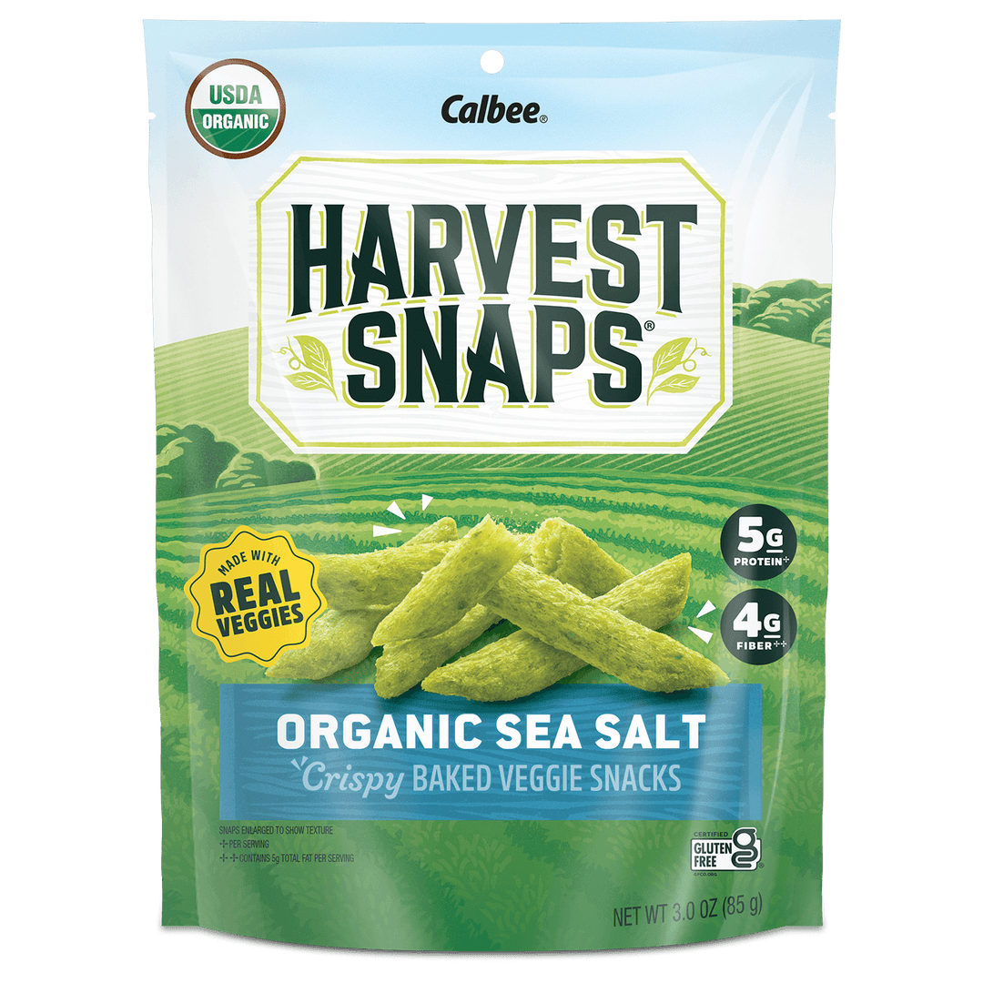 A bag of "Harvest Snaps" Organic Sea Salt veggie snacks. The package shows green pea crisps against a field backdrop. Promotes "Made with Real Veggies."