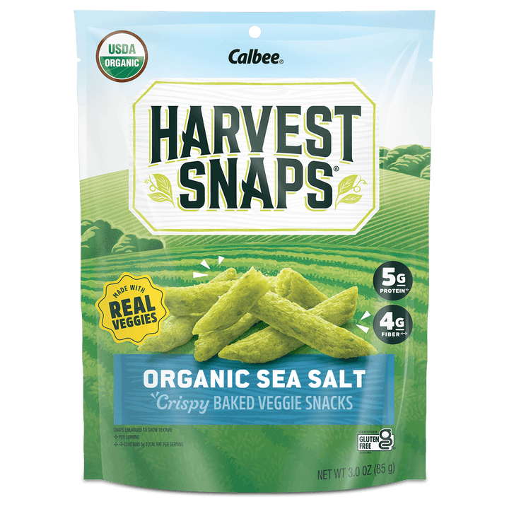 A bag of "Harvest Snaps" Organic Sea Salt veggie snacks. The package shows green pea crisps against a field backdrop. Promotes "Made with Real Veggies."