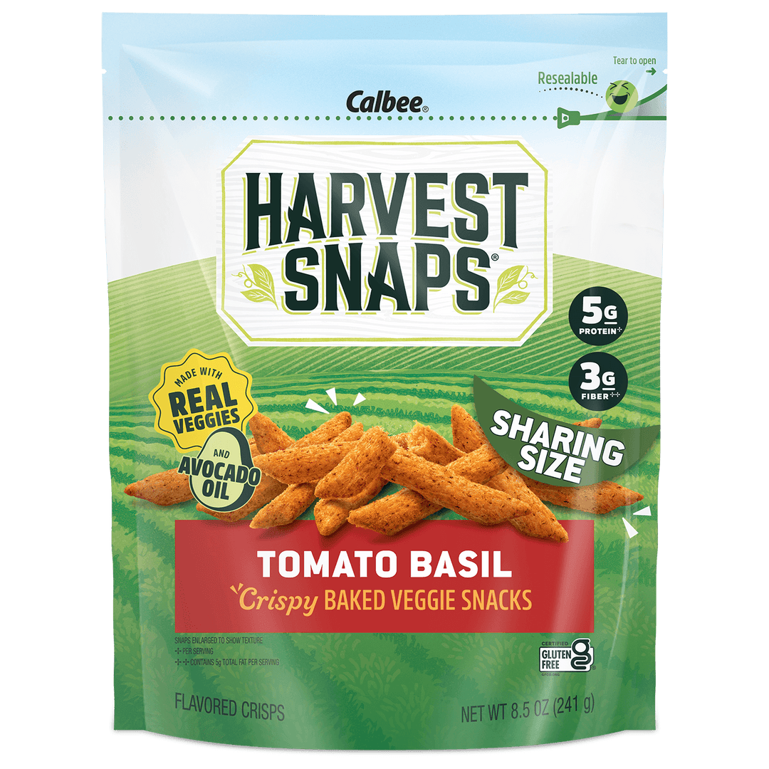A bag of Calbee Harvest Snaps Tomato Basil crispy baked veggie snacks, shown against a plain white background. The packaging features a green and white design with an illustration of the golden-brown snack pieces.
