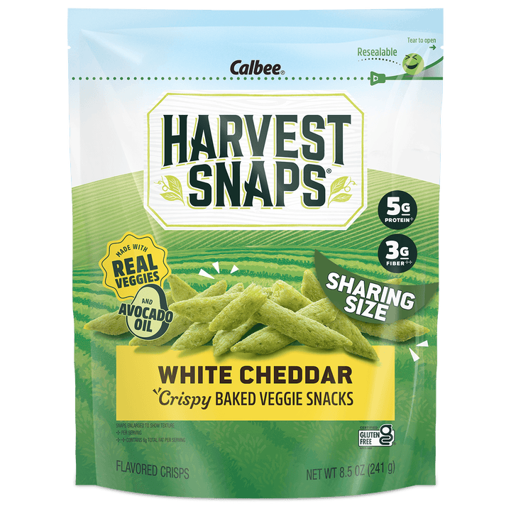 A package of Calbee Harvest Snaps White Cheddar Crispy Baked Veggie Snacks in a resealable stand-up pouch. The packaging is primarily green and white with a yellow banner at the bottom, showing images of the green veggie chips.