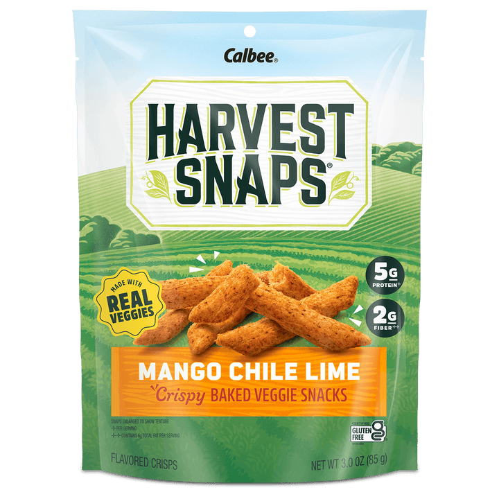 A package of Harvest Snaps Mango Chile Lime crispy baked veggie snacks. The design features a vibrant field background with product benefits like "5g protein" and "2g fiber."
