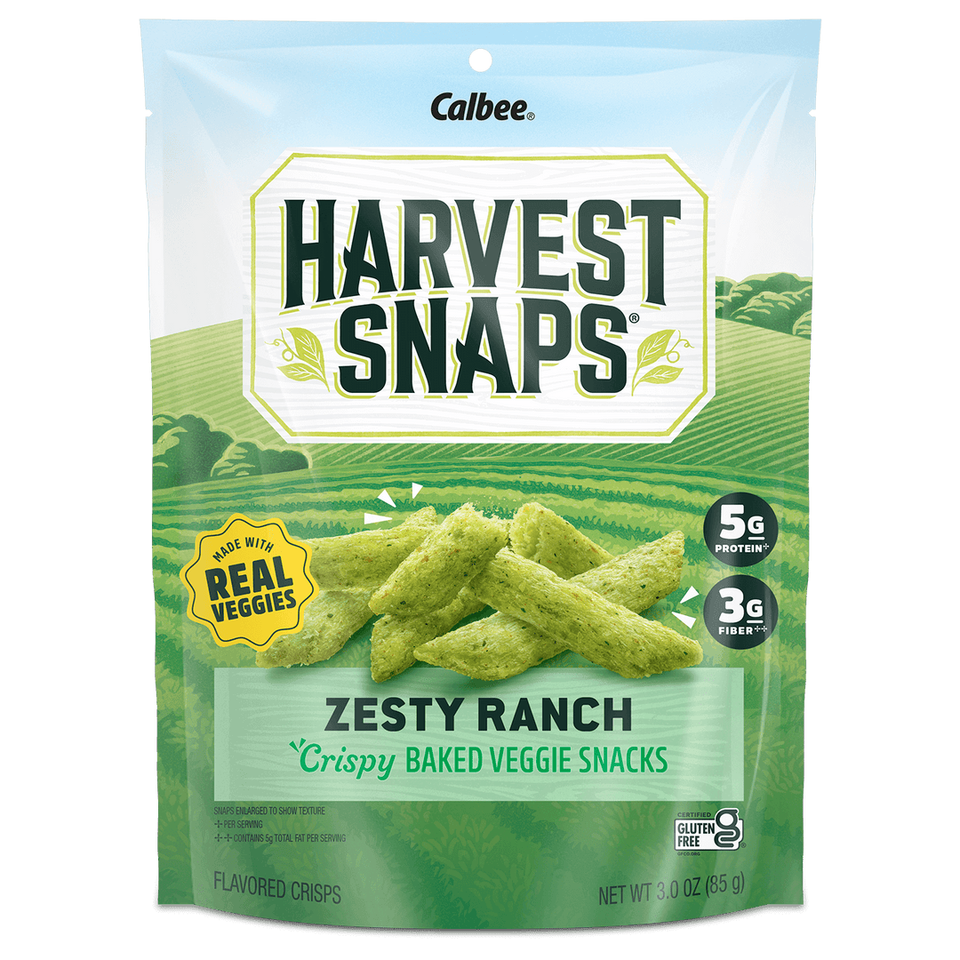 Bag of Harvest Snaps Zesty Ranch flavored veggie snacks, with green fields in the background. Labeled "made with real veggies," contains 5g protein and 3g fiber.